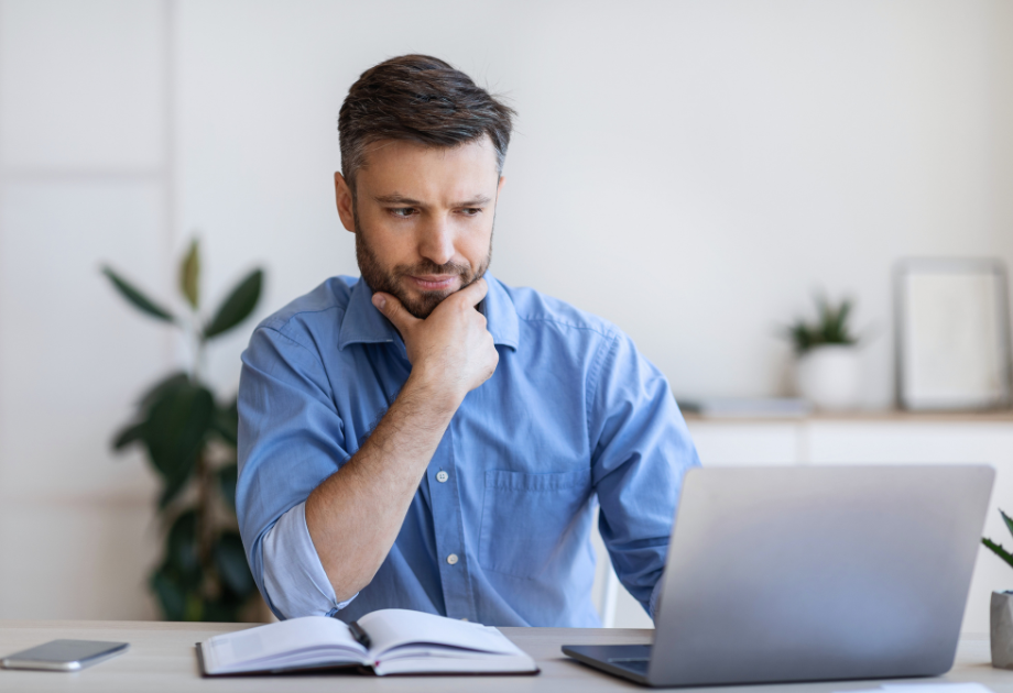 man with hand on chin looking at laptop